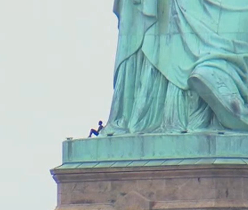 Illustration for article titled A Black Woman in Handcuffs For Climbing The Statue of Liberty on Independence Day is a Perfect Metaphor For America